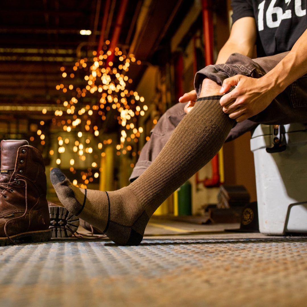 Person pulling on over-the-calf supportive socks from Darn Tough