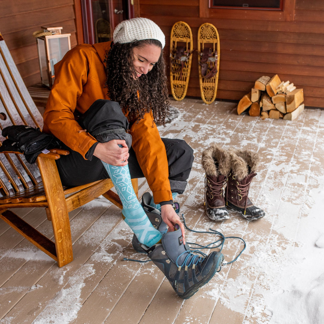 Woman on back porch pulling on boots over snow socks, getting ready for the new year