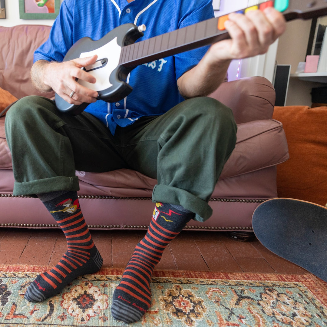 Person seated on couch playing Guitar Hero while wearing the Animal Haus socks