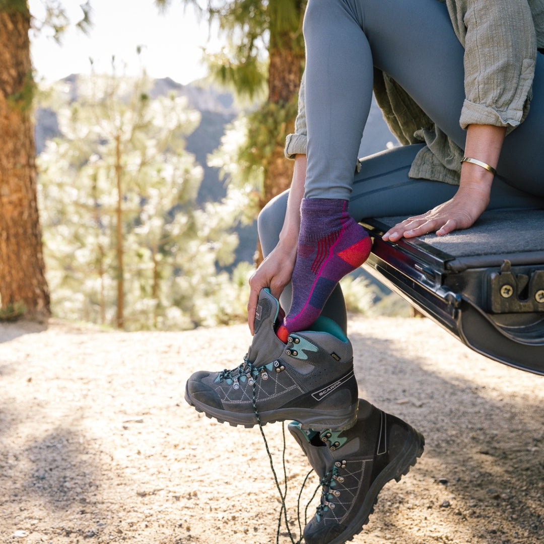 Hiker pulling on boots over purple hiking socks