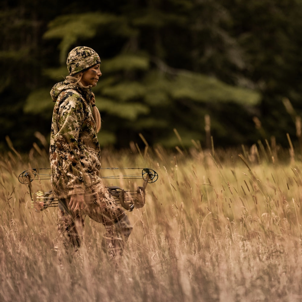female hunter Jamie Dragon dressed in camo and carrying a hunting bow