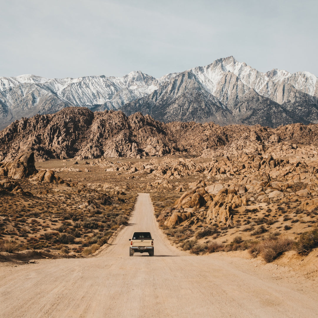 A car driving down a road toward a small mountain town, with epic vistas