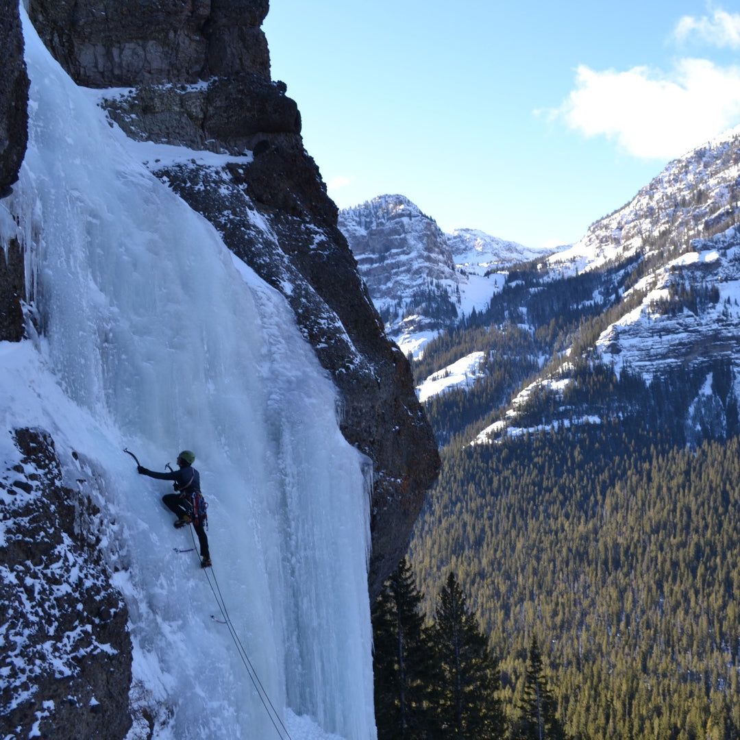 Ice climber partway up a dramatic frozen waterfall