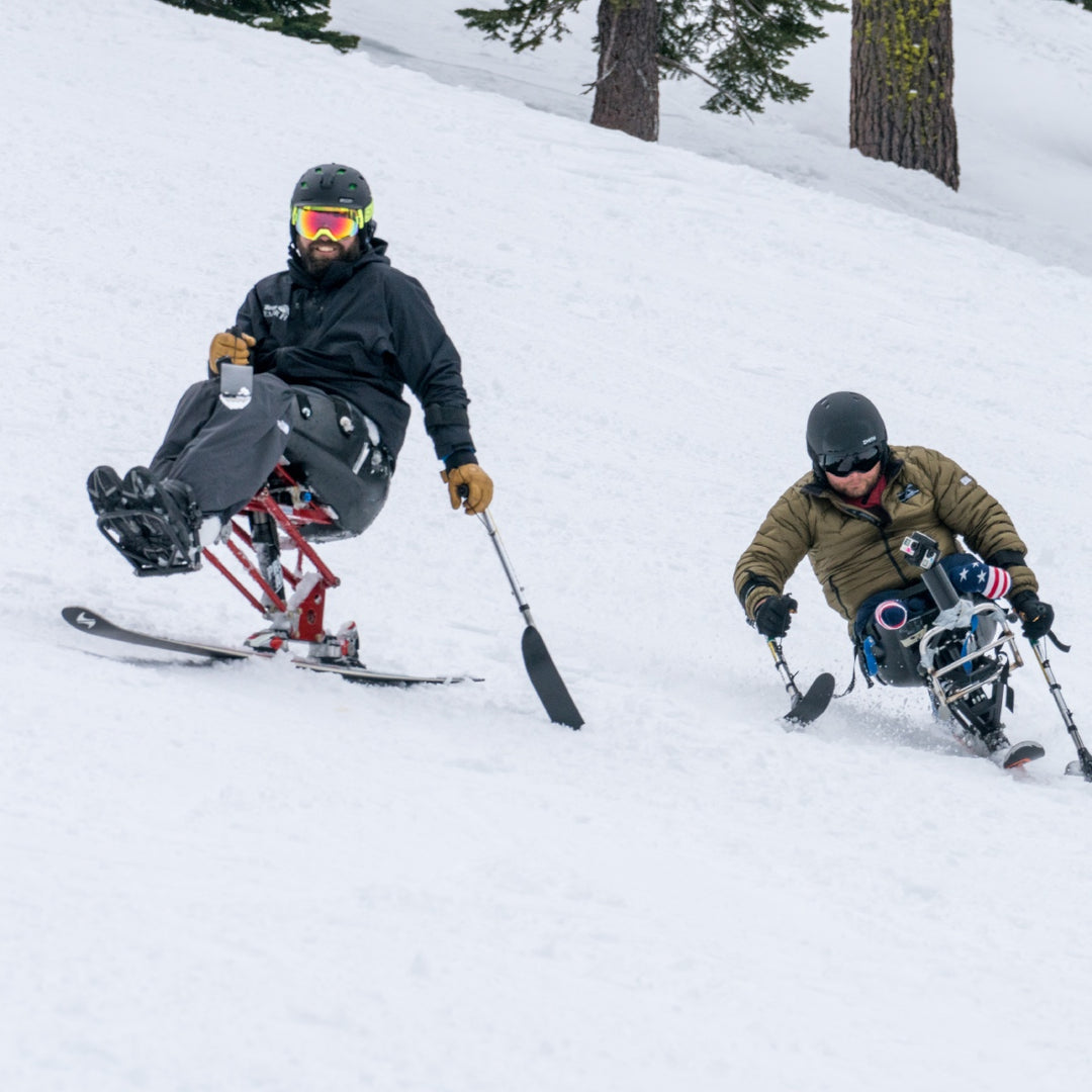 Two skiers on the slop using adaptive skis as part of a high five foundation event