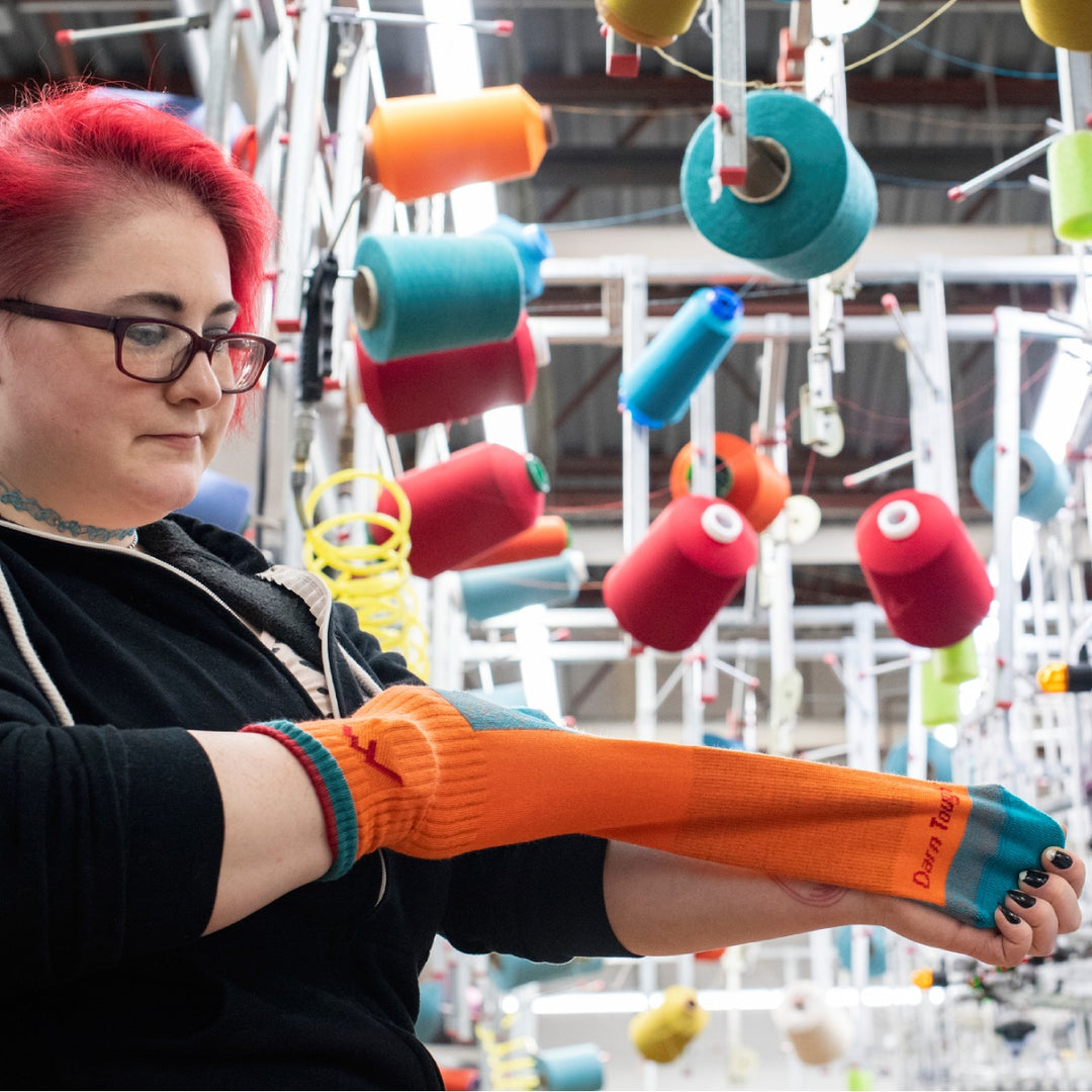 An employee at the Mill checking an overstock sock knit in bright orange