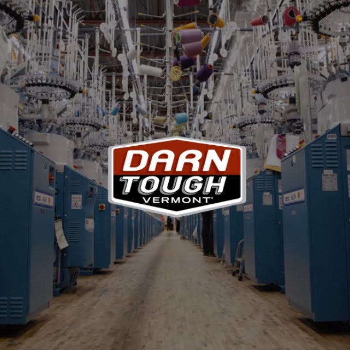 Darn Tough logo overlaid on a row of knitting machines from the Darn Tough Mill in Vermont