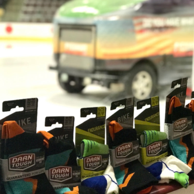 Darn Tough socks in front of a hockey rink with a zamboni on it