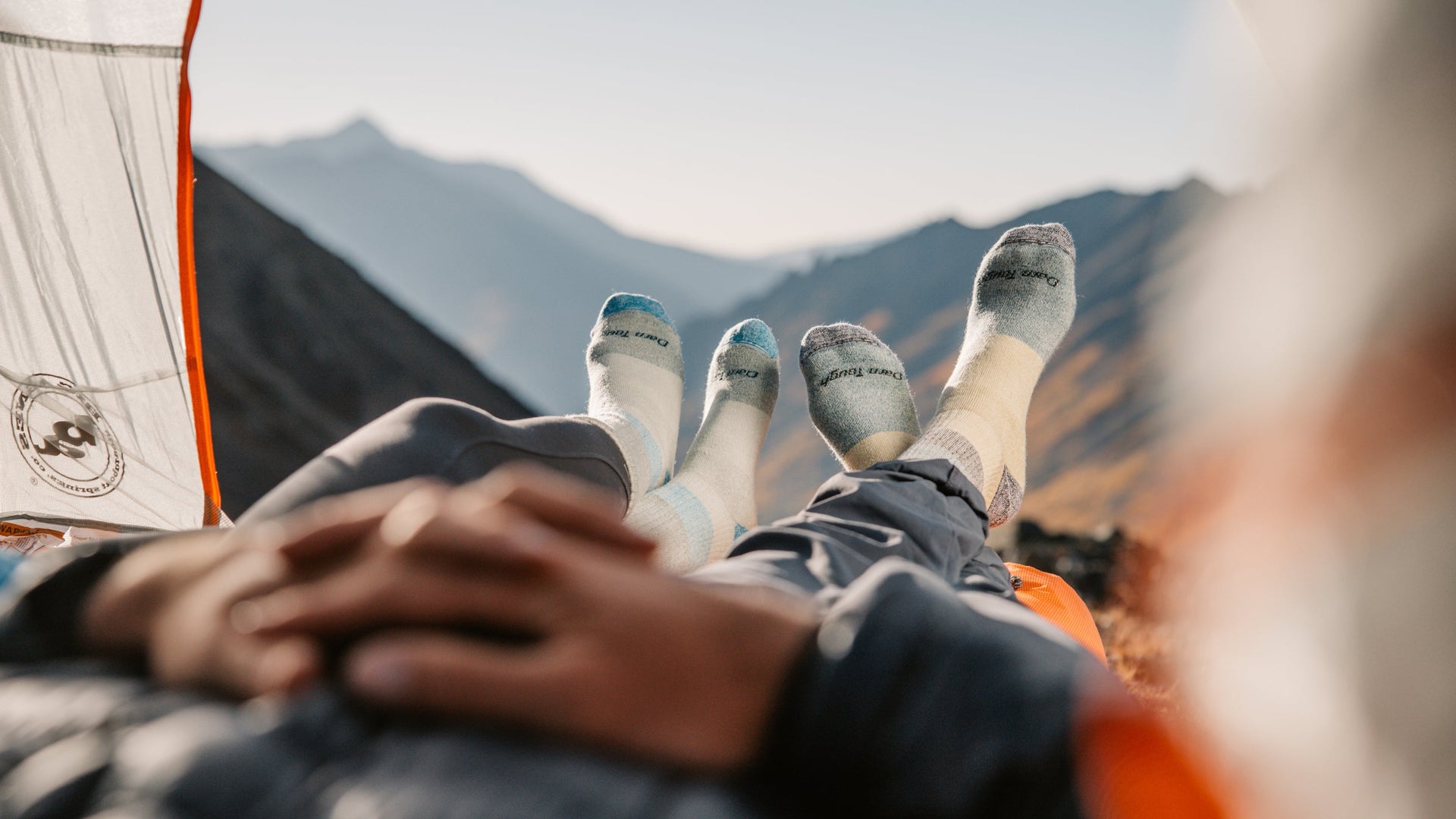 two model laying in a tent looking out at mountain wearing new heavyweight lifestyle