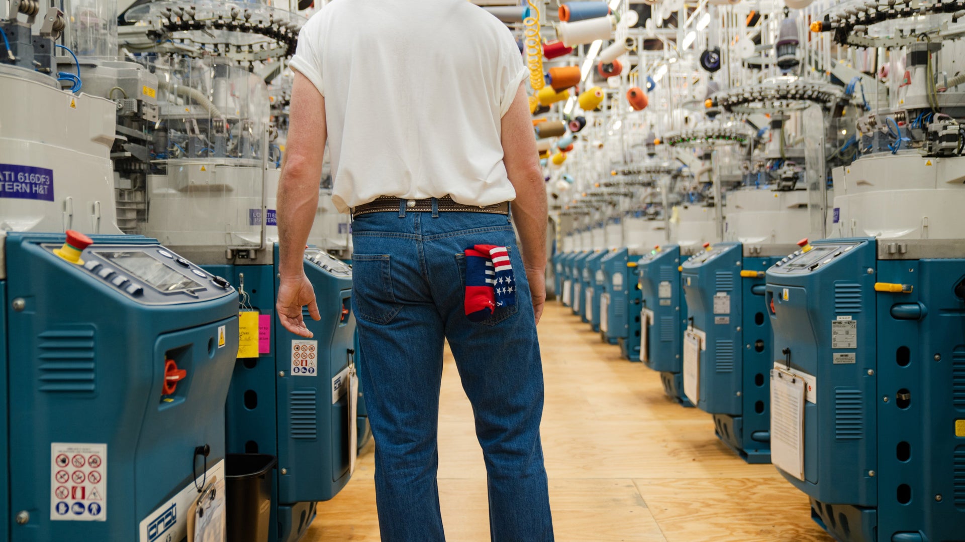 model stand infront of knitting machines with a captain stripe in back pocket