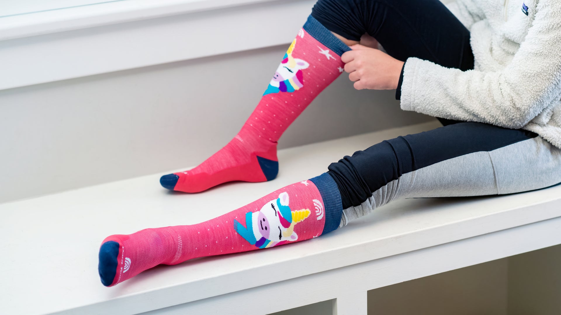 Model sitting on Bench one leg up pulling up the Magic Mountain snow sock