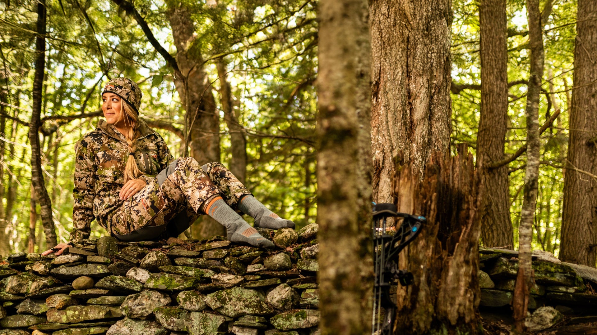 women sitting on rock wall in camo wearing lightweight hunting boot socks