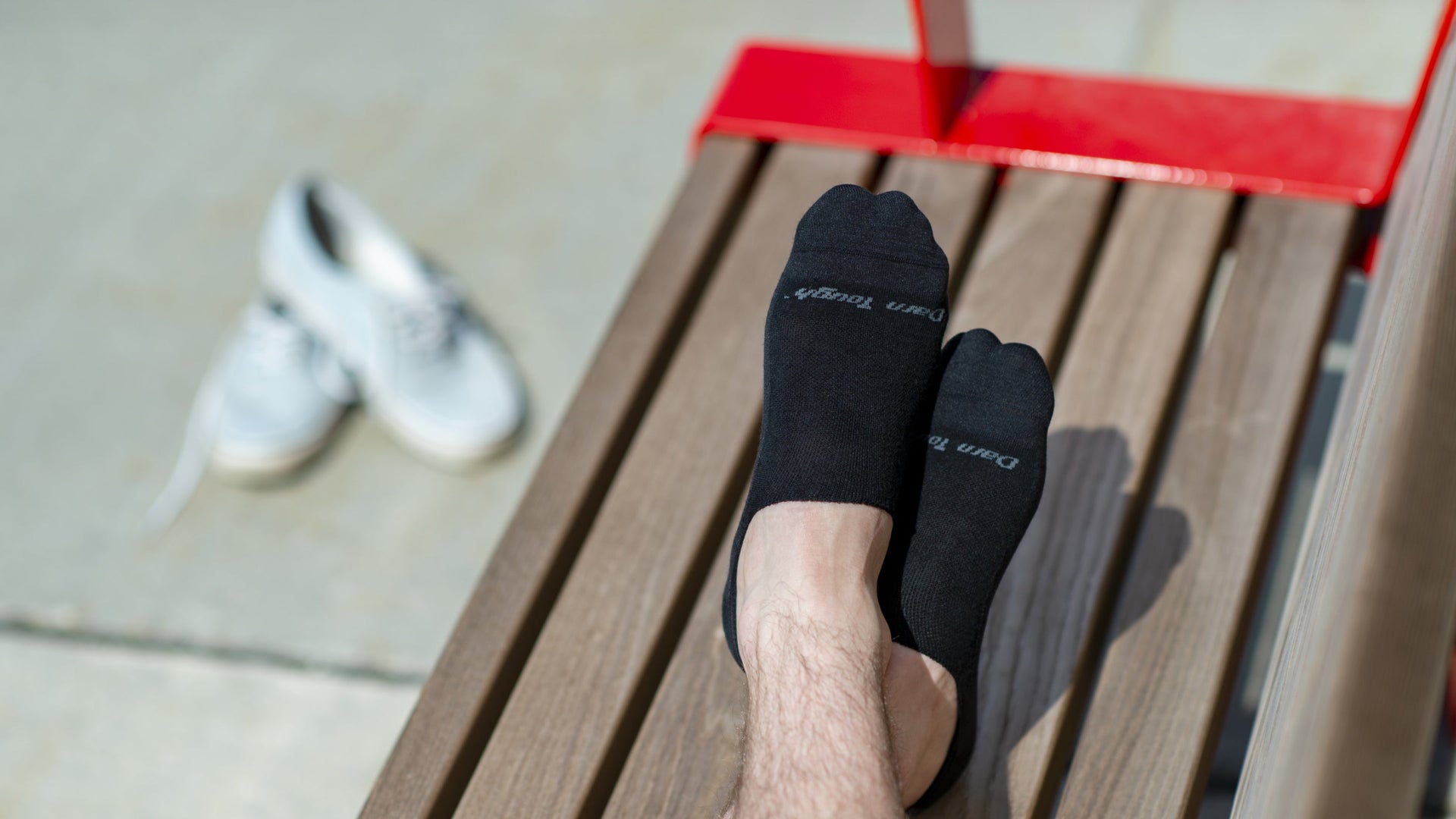 Models feet up on bench wearing the 6055 No show hidden lifestyle sock