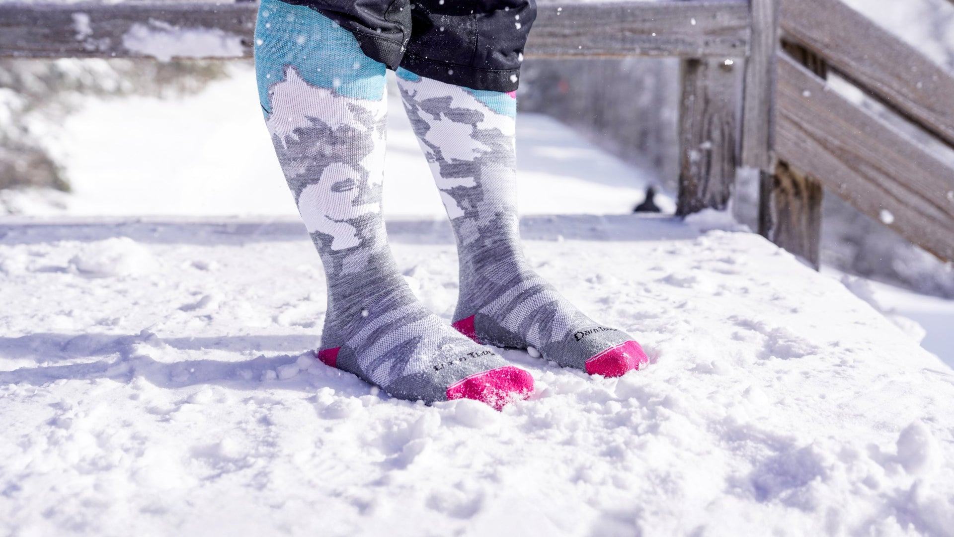 Model standing in the snow wearing the Over the calf Yeti sock