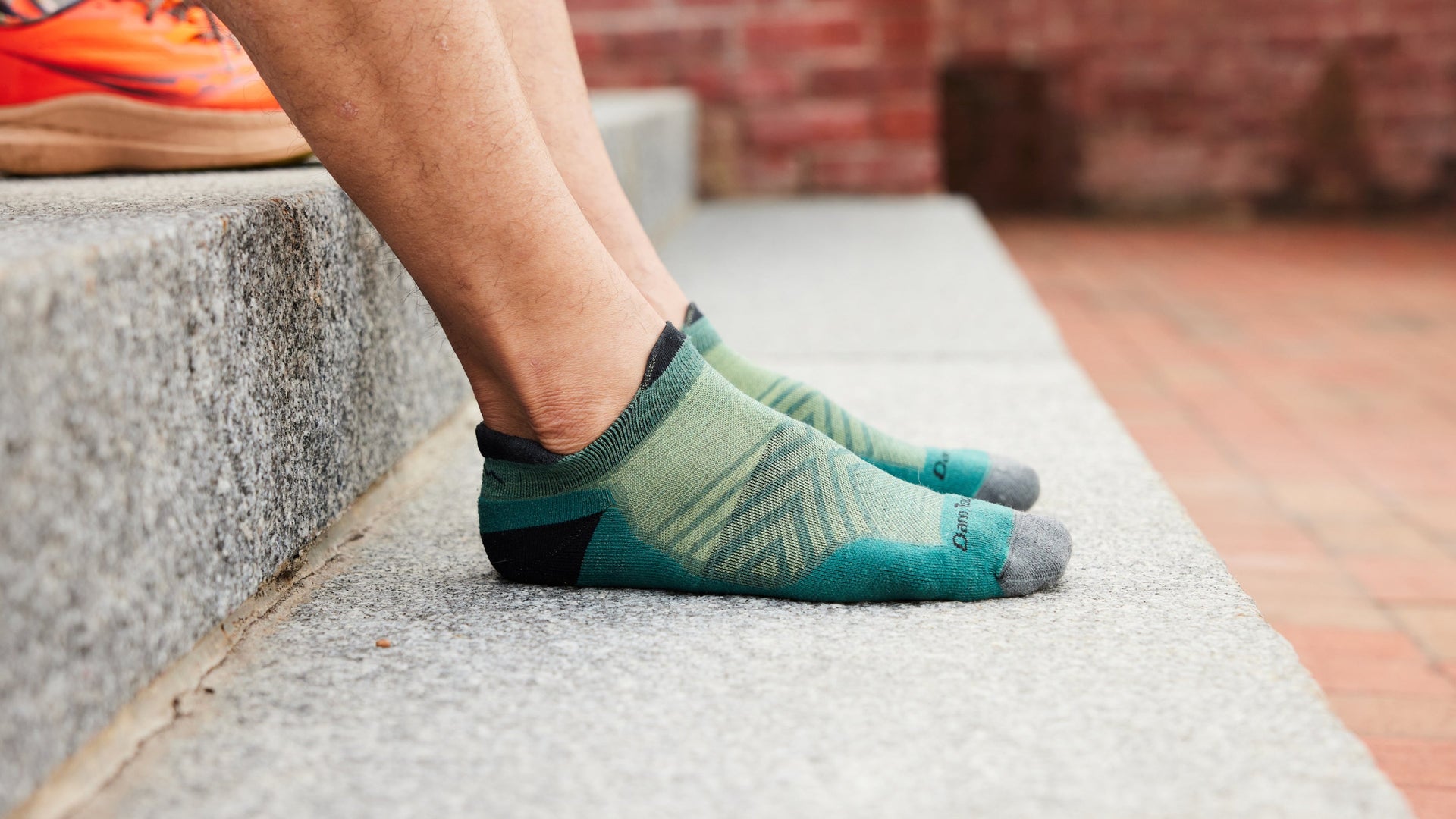 models feet on granite steps wearing the men's 1039 ultralight no show running sock
