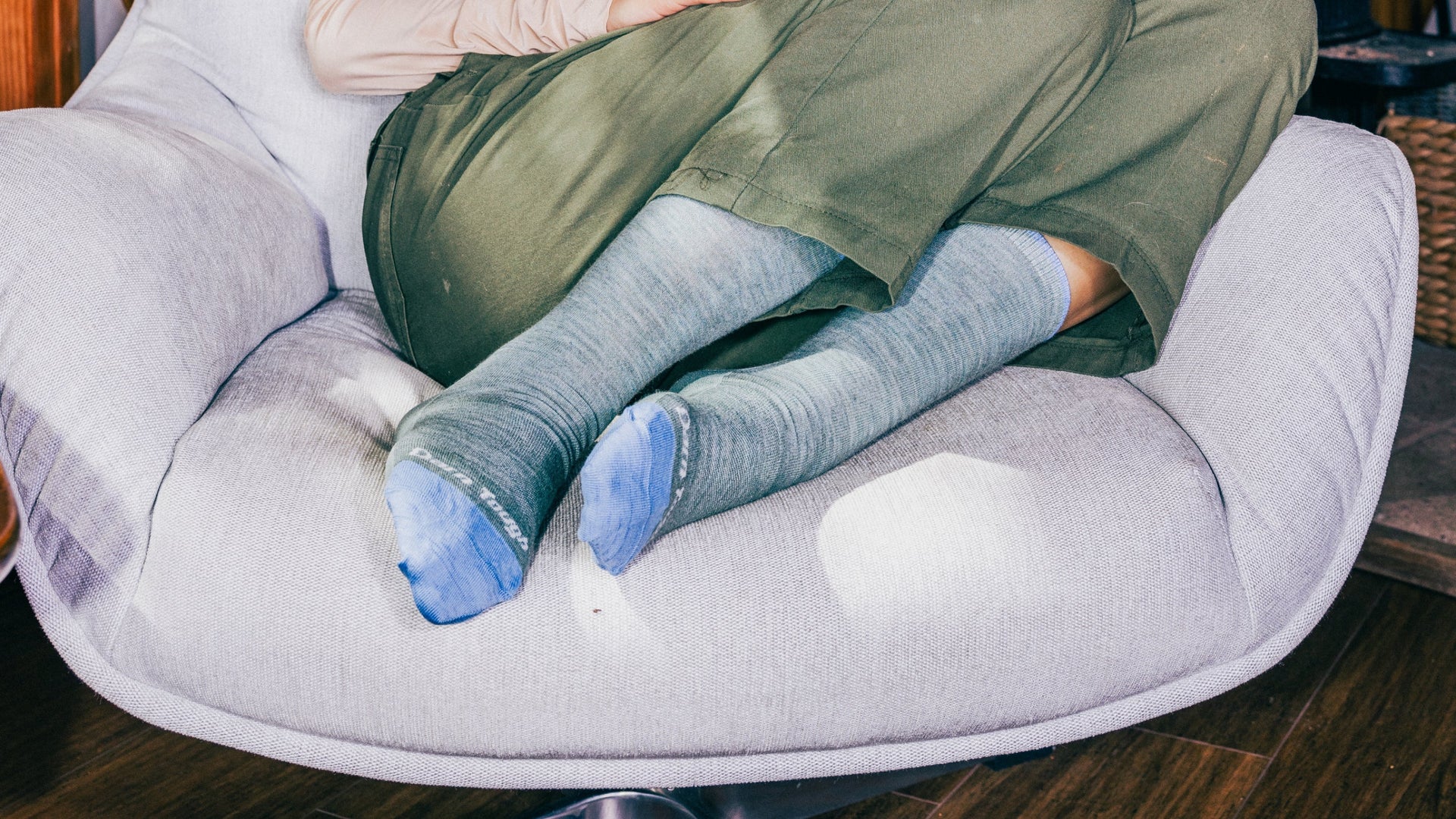 model sitting in padded chair with feet curled up wearing the solid crew lifestyle sock