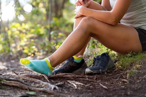 A woman seated on the ground wearing coolmax socks, synthetic running socks that are also vegan