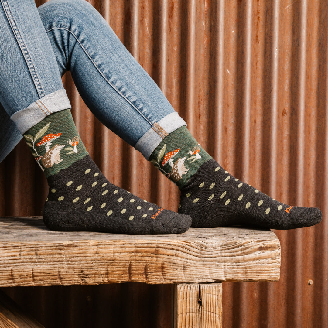 model feet up on a bench wearing the 6105 wild life crew in hedgehog moss featuring a green body with dot and animal scene on ankle