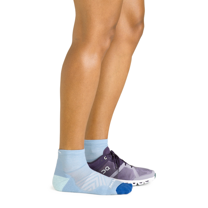 Side shot of model wearing the women's quarter running sock in sky blue with a purple sneaker on her left foot