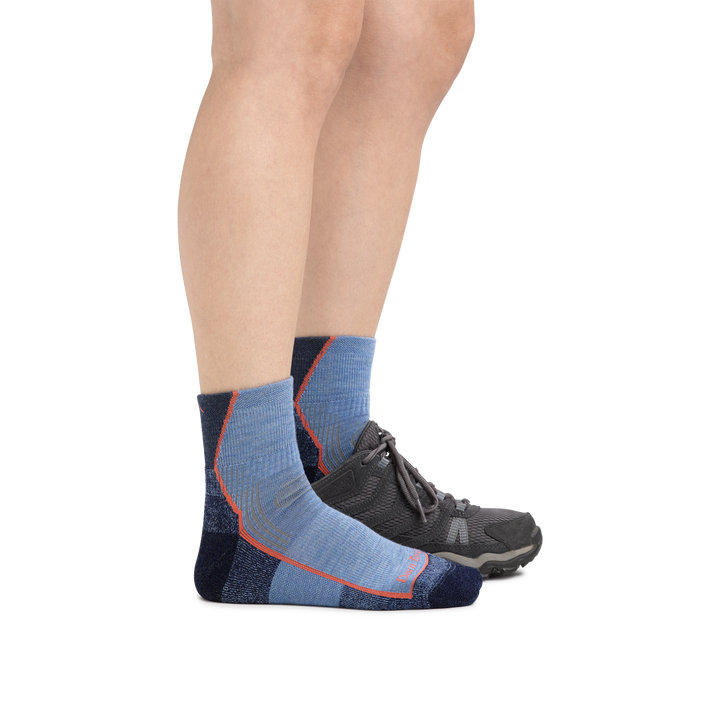 Woman wearing Women's Hiker Quarter Midweight Hiking Socks in Denim Heather and a hiking shoe on one foot
