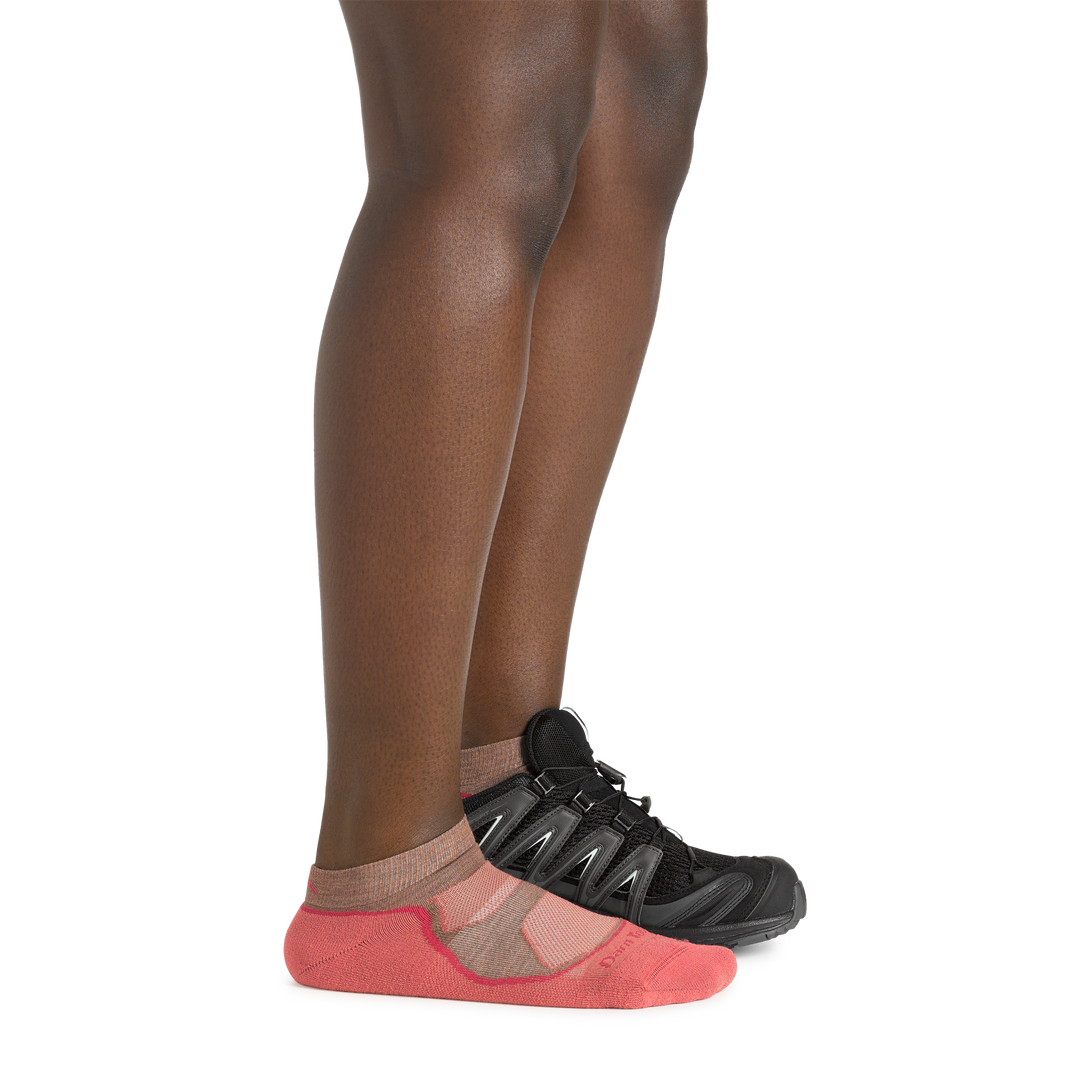 Profile image of a woman's legs on a white background, wearing Women's Light Hiker No Show Lightweight Hiking Socks in Canyon colorway, with one foot also in a hiking shoe