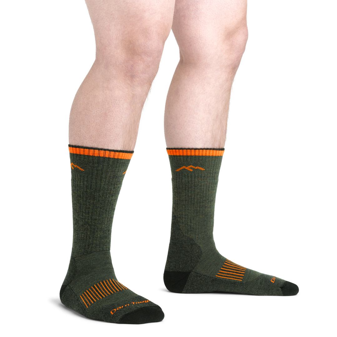 On model image of 2111 Midweight Hunting Boot Sock in Forest colorway with green body and black and orange accents