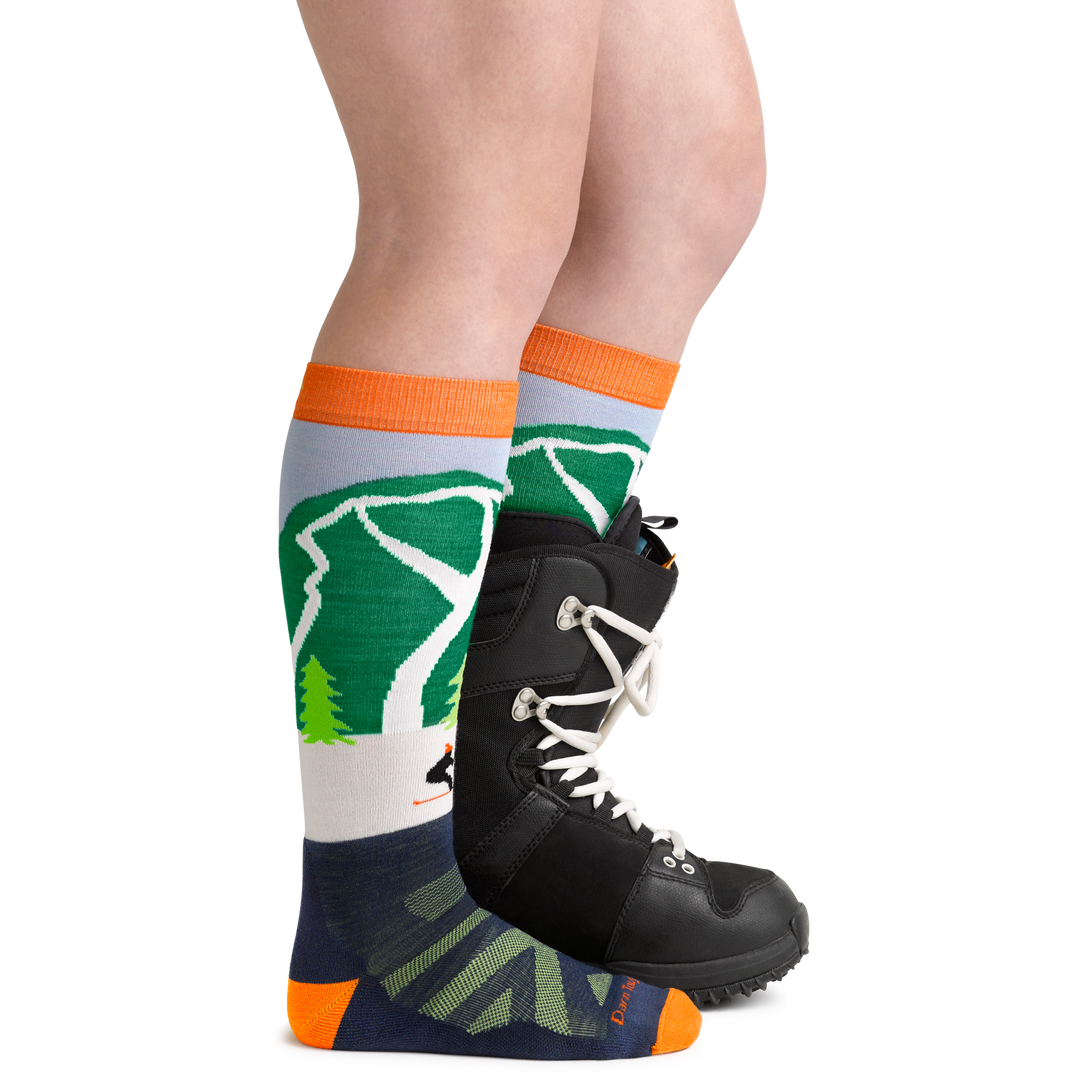 Cow Pow Kids' Snowboard and Ski Sock in Green on foot with snowboard boot