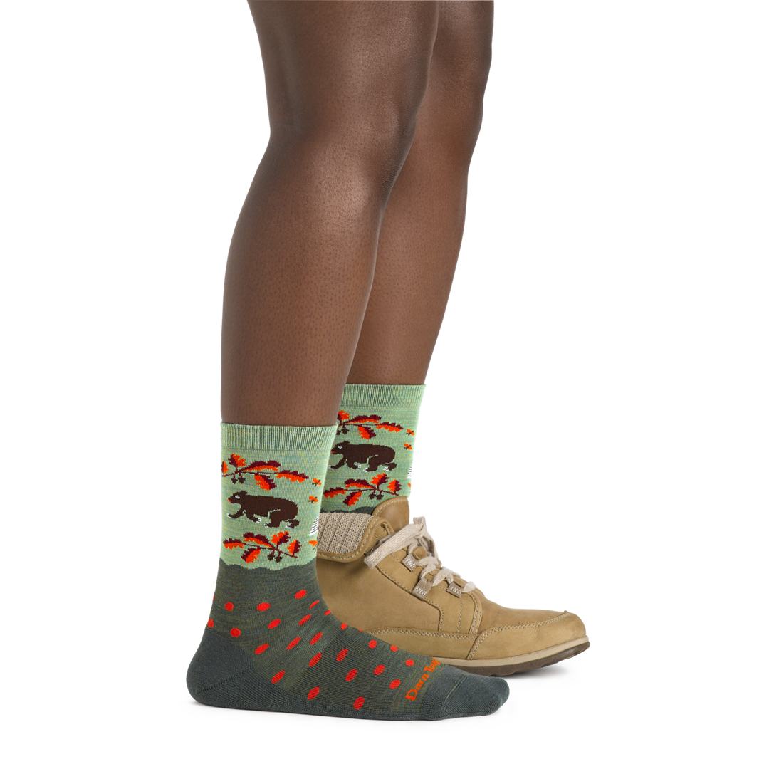 Side shot of model wearing the women's wild life crew lifestyle socks in forest with a tan boot on her left foot