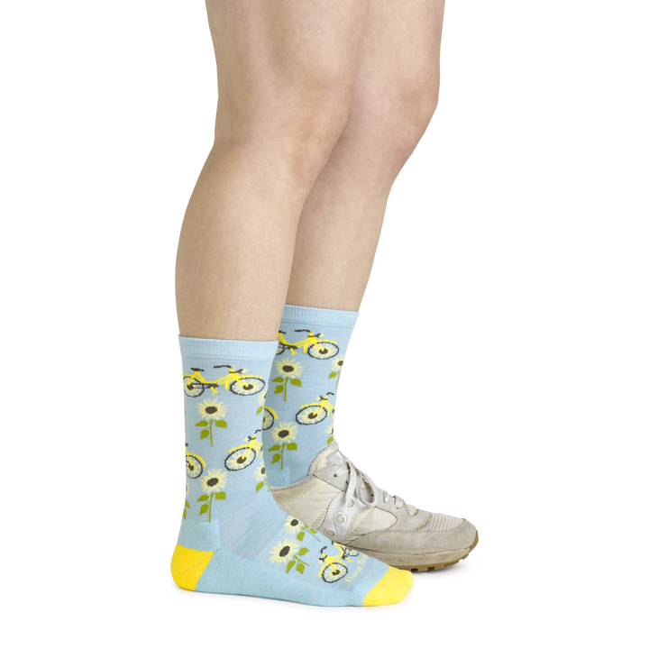 Model wearing the women's sun pedal crew lifestyle socks in glacier blue with a white sneaker on her left foot
