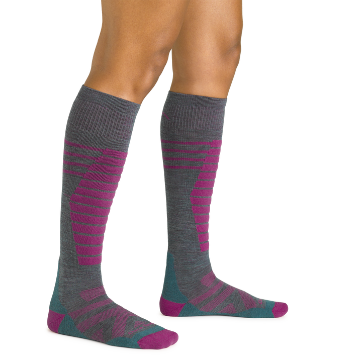 Close up studio shot of model wearing women's edge over-the-calf midweight ski & snowboard sock in teal and pink