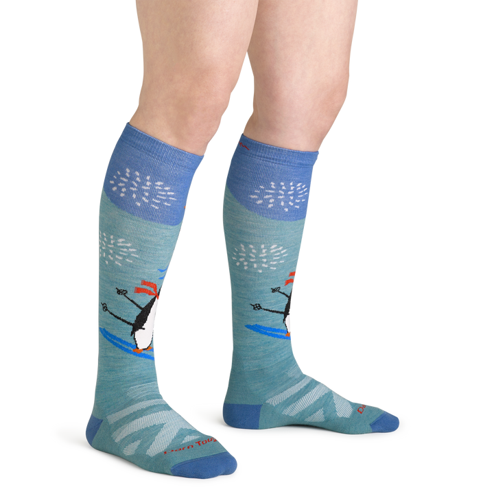 Close up studio shot of model wearing women's penguin peak over-the-calf midweight ski & snowboard sock in aqua