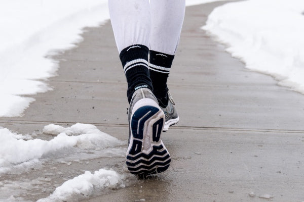 Feet wearing padded athletic running socks on a snowy day