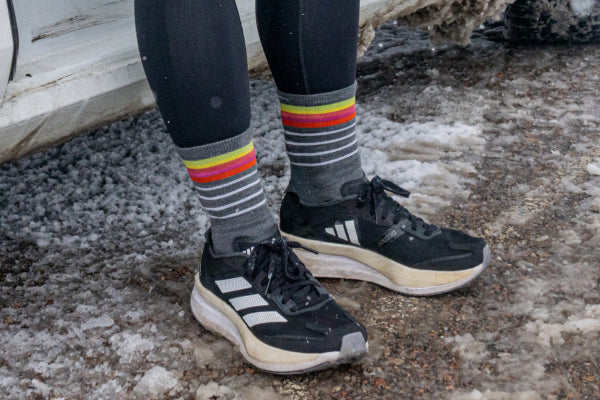 Feet in running shoes wearing micro crew socks with stripes