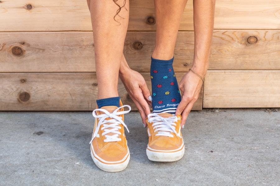 Women's feet putting on low top sneakers over the lucky lady no show socks for casual