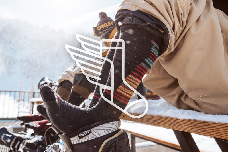 Skiers and snowboarders resting their feet on their boots, showing their merino wool ski socks
