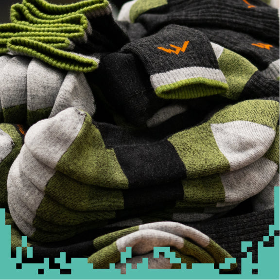 A giant pile of merino wool socks from Darn Tough, looking warm and cozy
