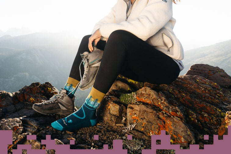 Shop Warm Socks for Winter - hiker on rocky summit in darn tough hiking socks