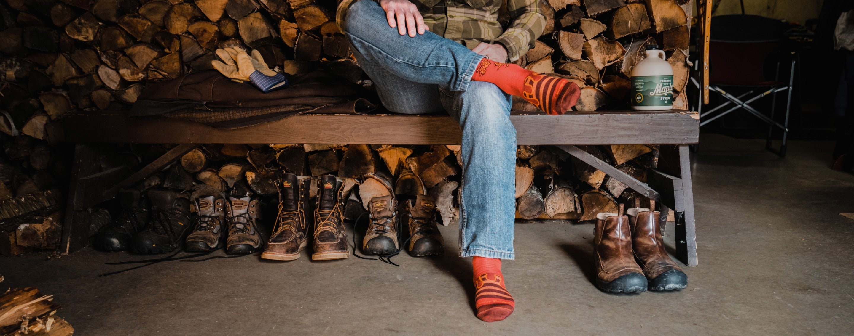 Person seated on a bench wearing Darn Tough socks with a maple syrup design