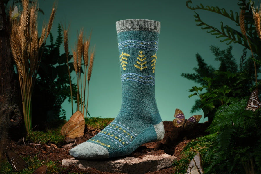 A teal sock covered in grain designs and heart-shaped seeds
