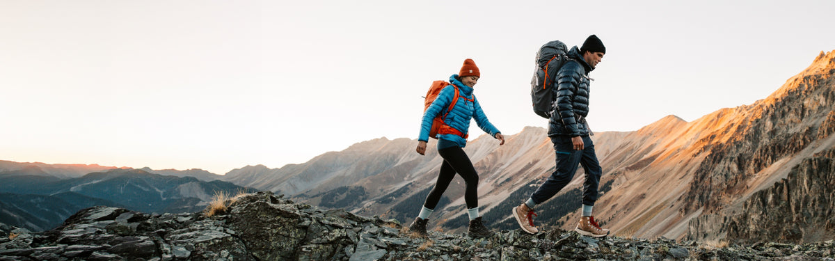 Two hikers on a rocky ridge wearing Darn Tough hiking socks