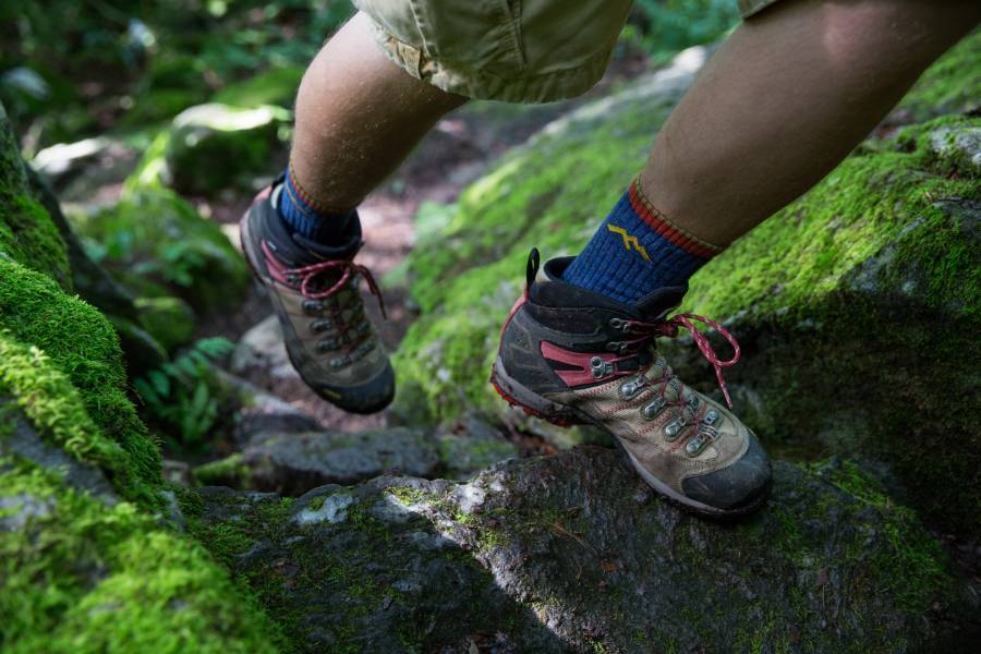 Hiker going up on a rocky trail in darn tough socks for hiking, the most comfortable hiking socks
