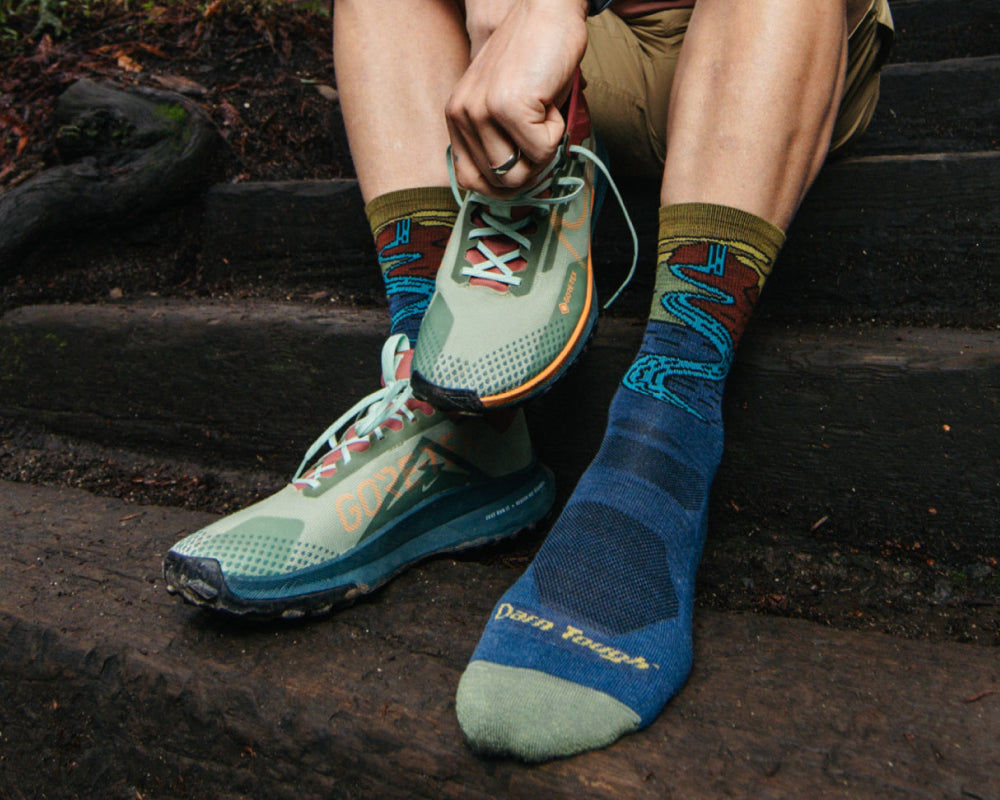A pair of made in USA socks featuring a waterfall design, worn by a hiker