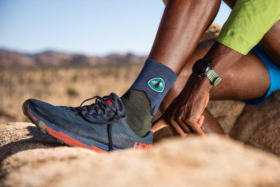 Hiker with foot up in hiking shoes wearing the CDT darn tough socks for hiking