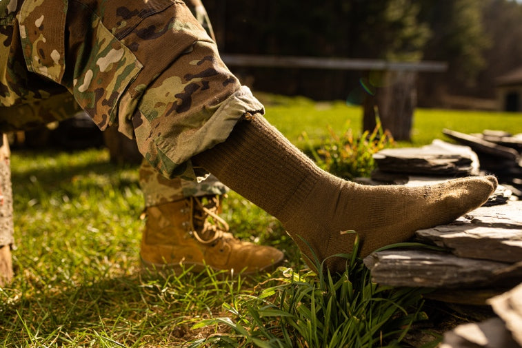 Shop Tactical socks - legs in combat fatigues, foot out with a tactical sock on