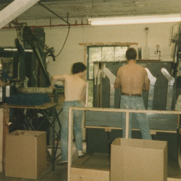 Two men working at the Mill back in the 80s, putting socks on the boarding machine