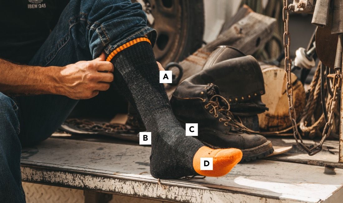 Worker pulling on darn tough socks for steel toe boots, the best wool socks for work