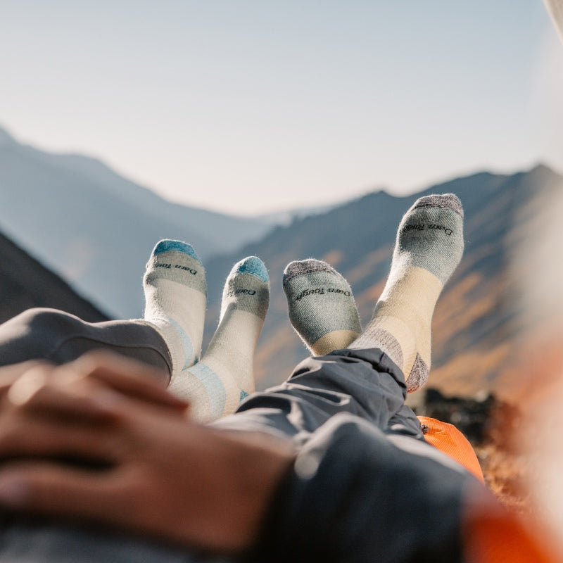 Two pairs of feet wearing extremely cozy Merino Wool socks while out camping