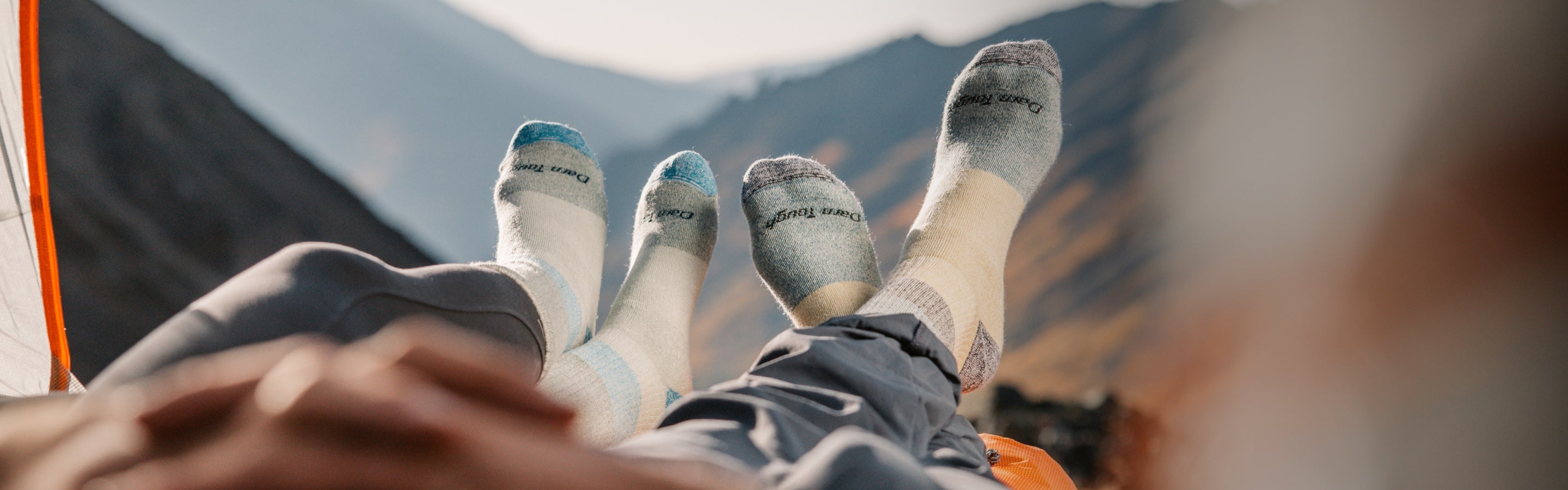Two pairs of feet wearing extremely cozy Merino Wool socks while out camping