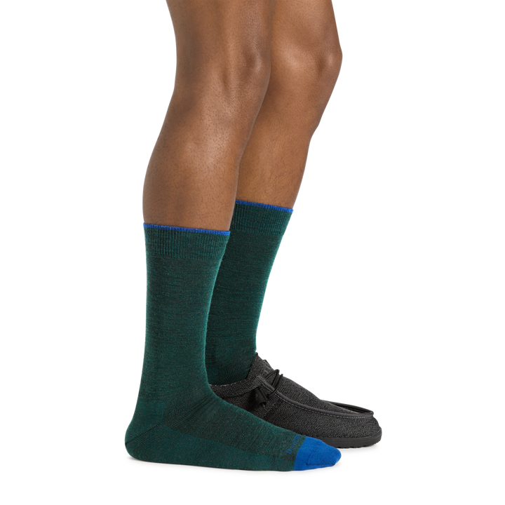 Model wearing the Men's Solid Crew Lightweight Lifestyle Sock in Bottle with a black loafer on onefoot