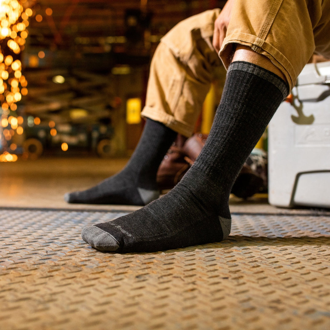 Side shot of model with no shoes on wearing the men's john henry boot work sock in gravel with tan pants on