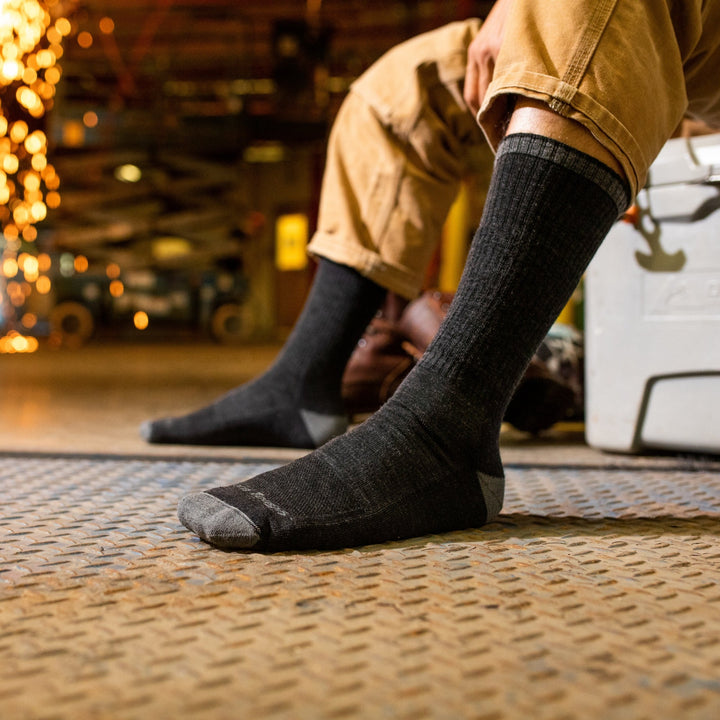 Side shot of model with no shoes on wearing the men's john henry boot work sock in gravel with tan pants on
